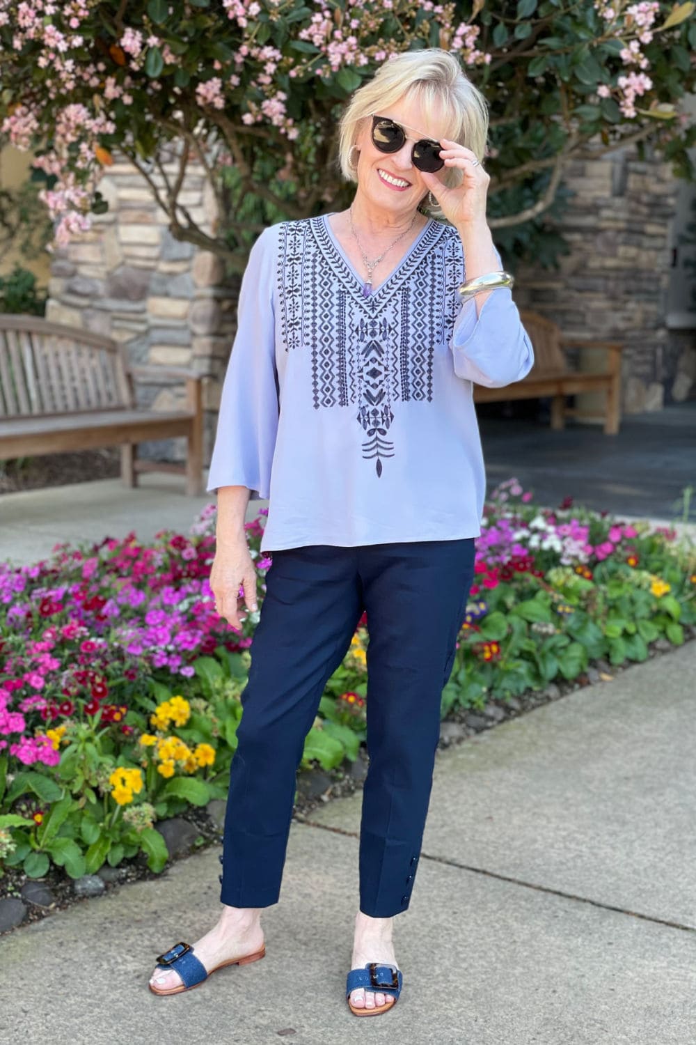 fashion blogger jennifer of a well styled life wearing sunglasses, purple embroidered top and denim sandals