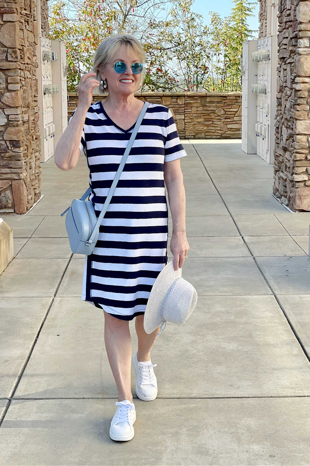 woman holding straw hat and walking towards the camera