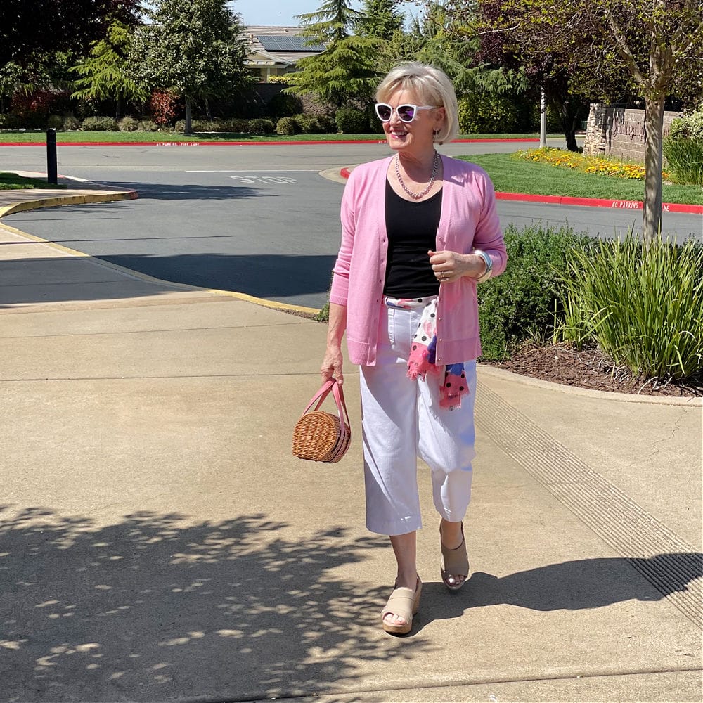 woman walking in white chino's and pink cardrigan
