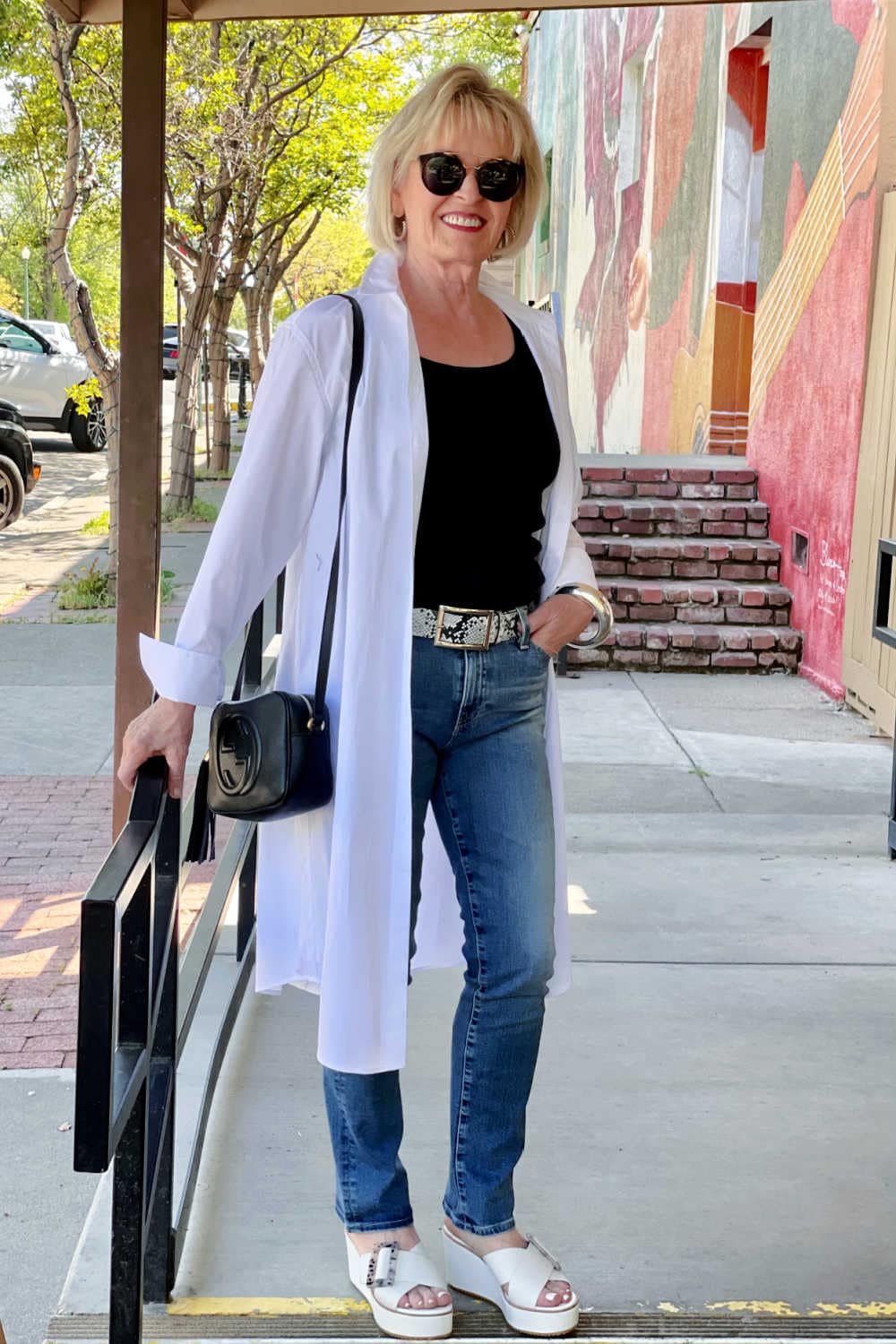 woman in white duster and blue jeans on steps