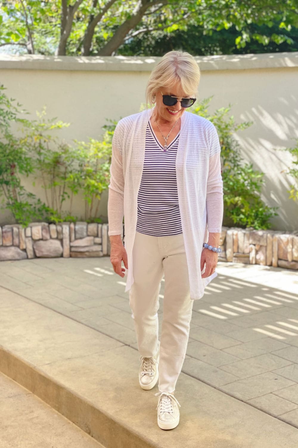 woman walking in courtyard wearing modern white jeans and striped tee