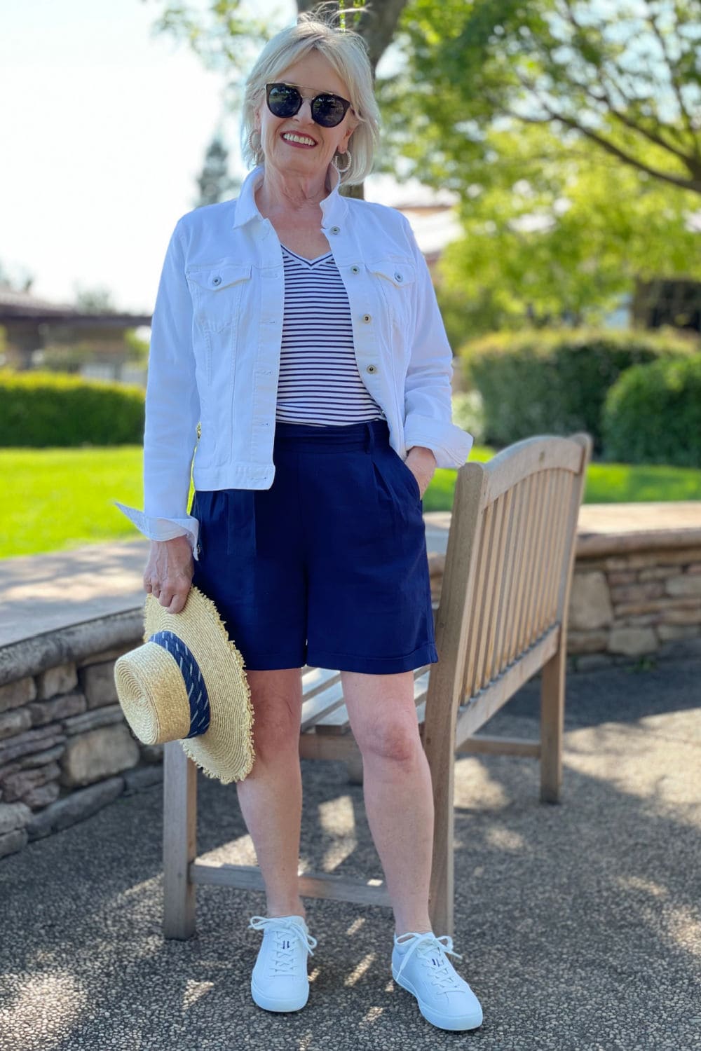 jennifer of a well styled life wearign navy pleated shorts and rothy's sneakers