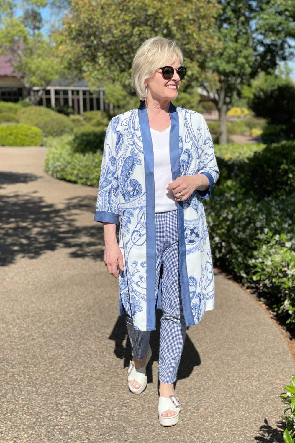 woman walking in sun wearing white tee, blue and white kimono and blue and white houndstooth pants