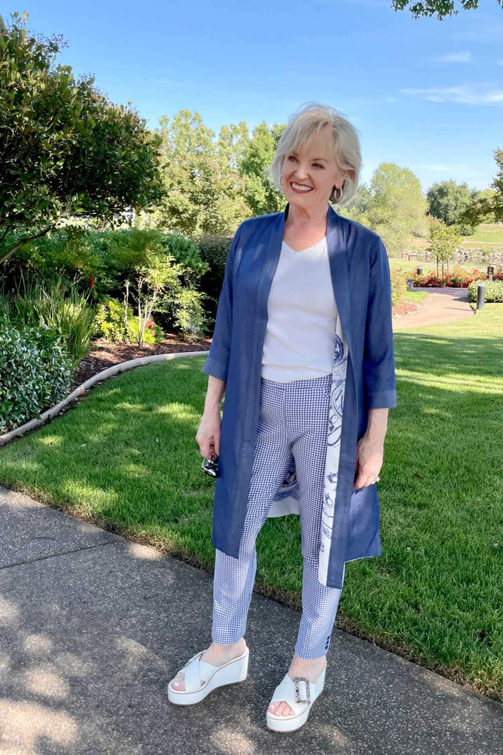 blond woman wearign blue duster and plaind pants with white shoes