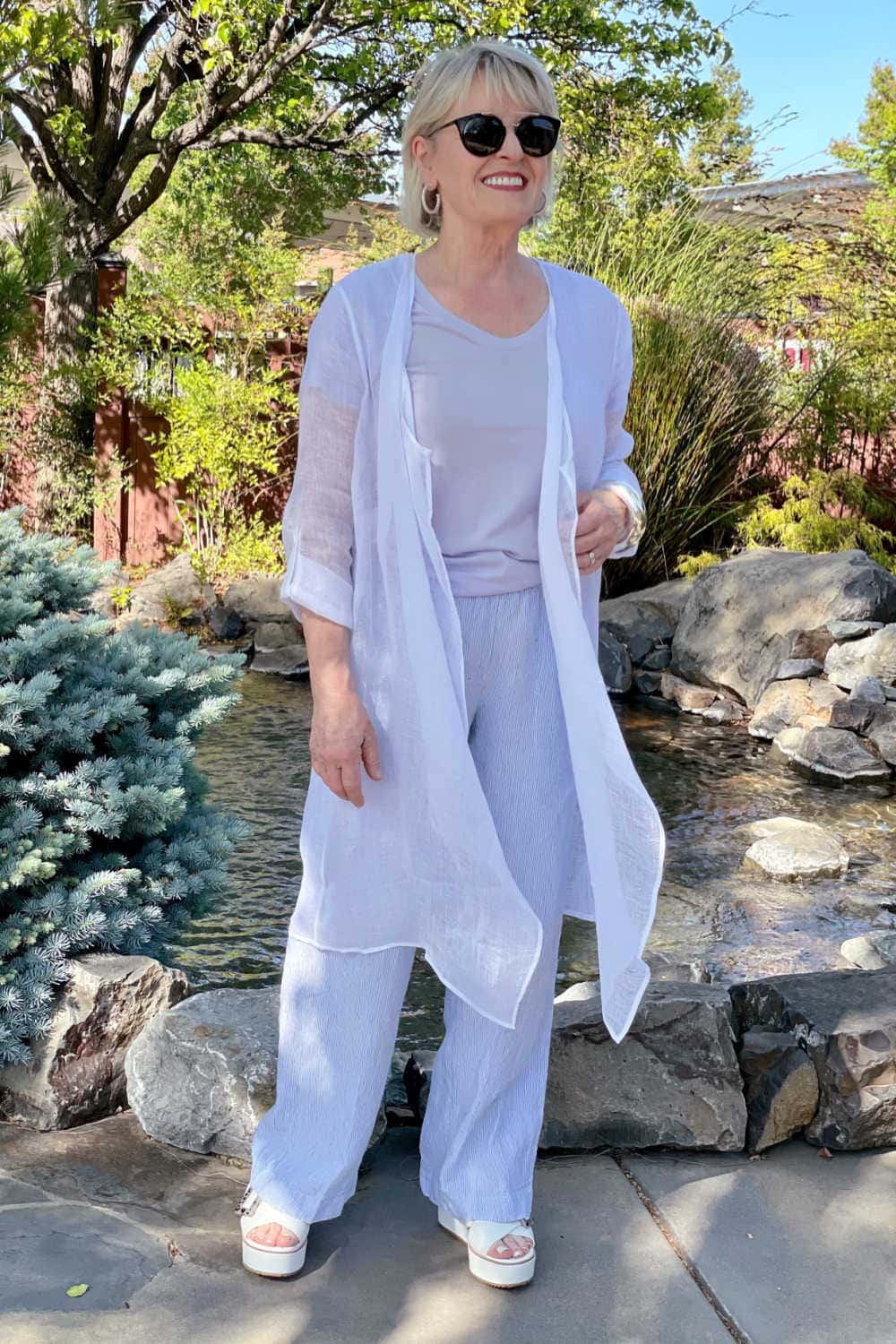 woman standing ion frotn of fountaion wearing gauzy linen duster and linen pants