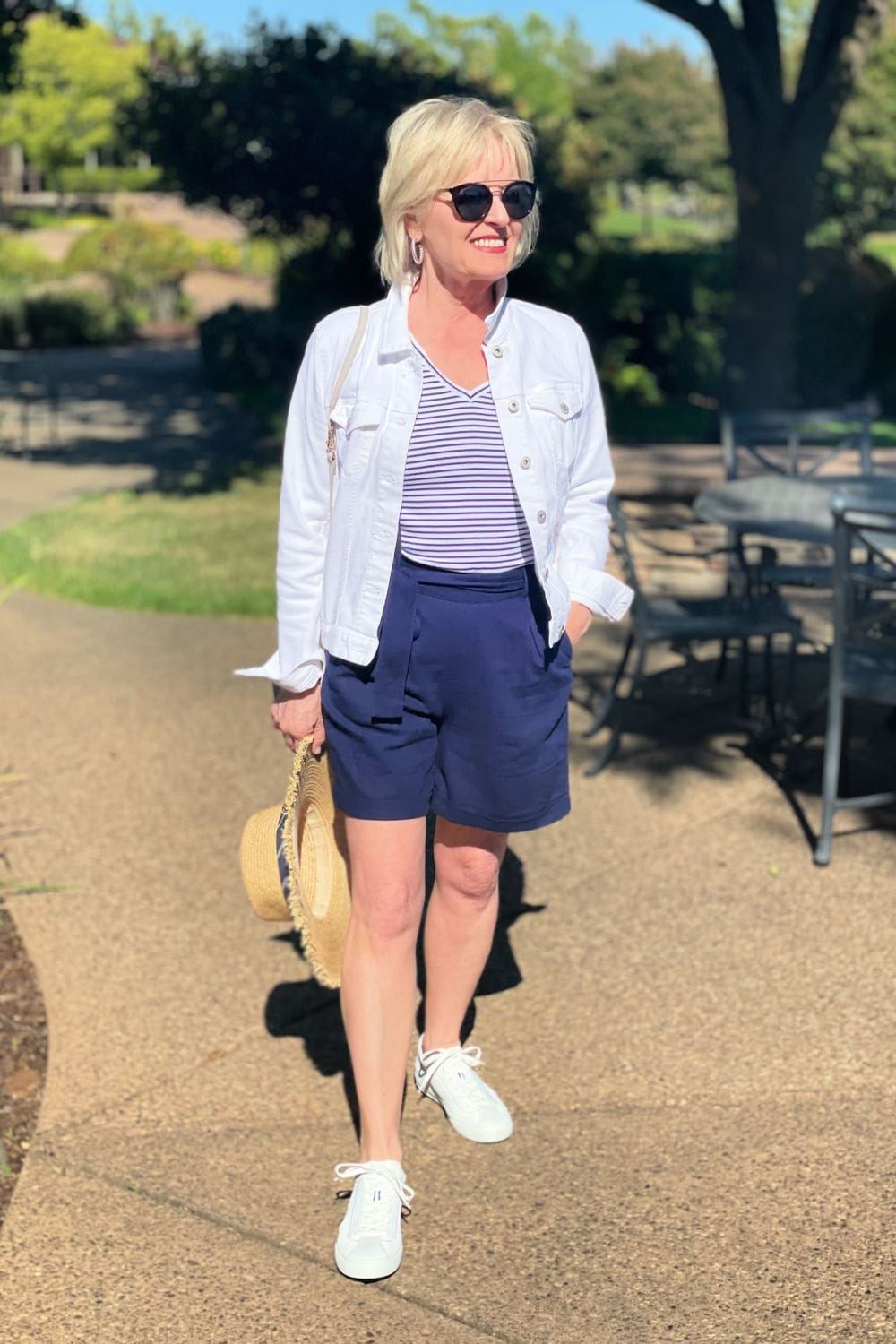 over 50 blogger wearing navy shorts with white sneakers and striped tee