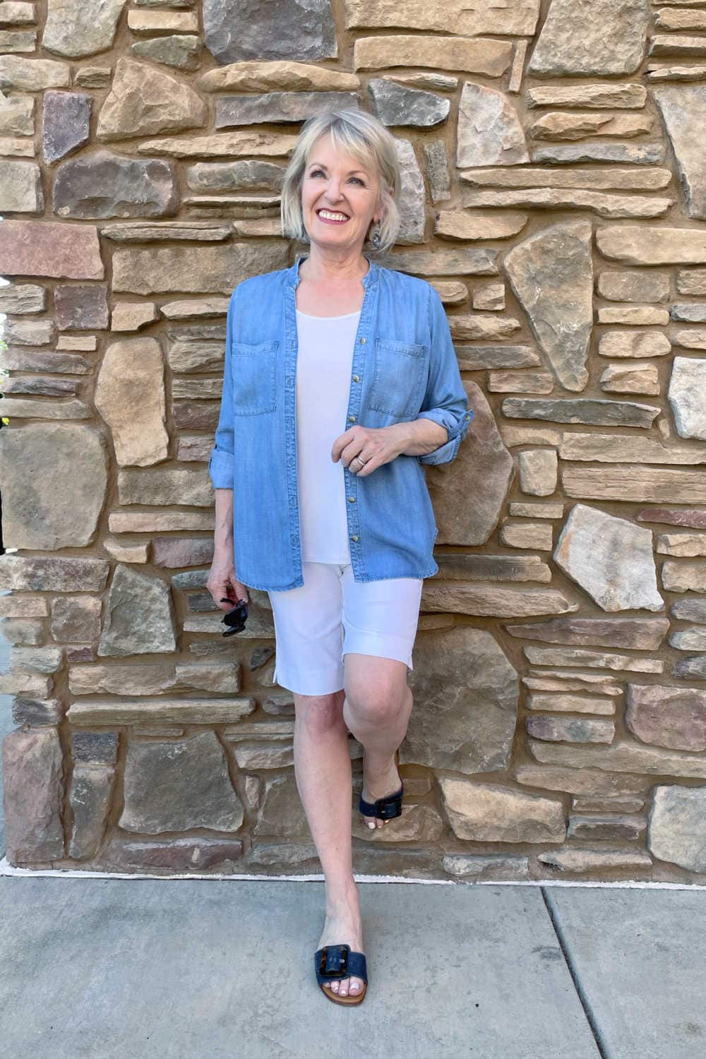 woman leaning against wall wearing denim top and stretch shorts