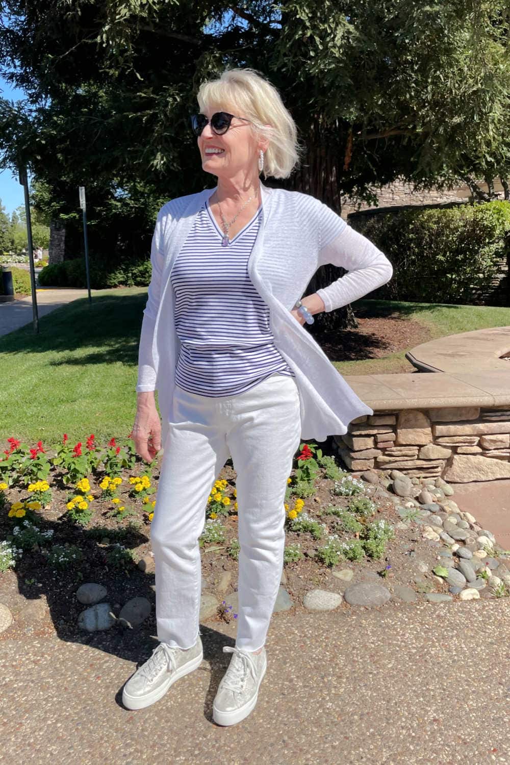 woman standing in front of tree wearing white jeans, striped tee and metallic sneakers