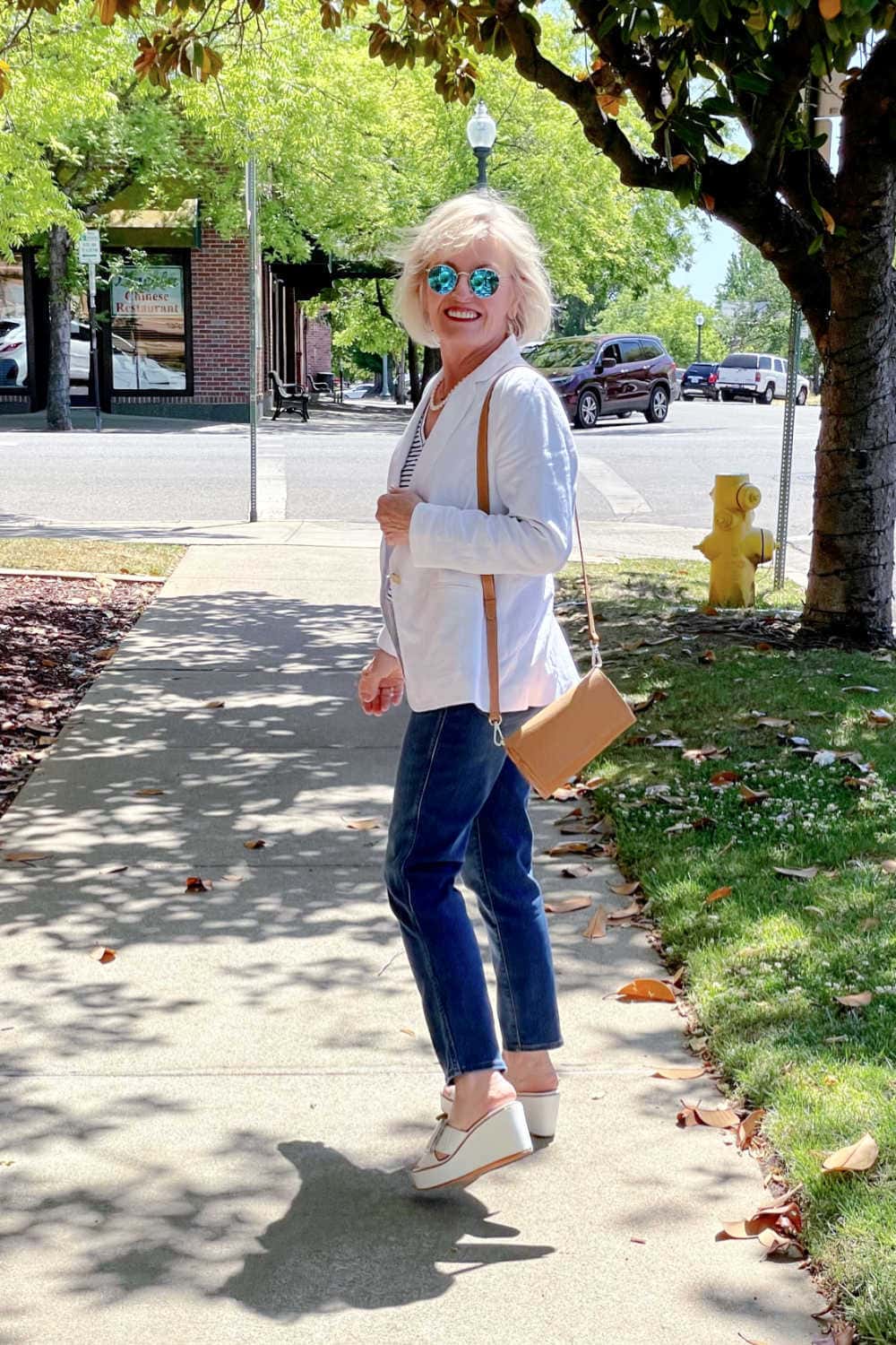 woman looking over her shoulder wearing blue jeans and white linen blazer