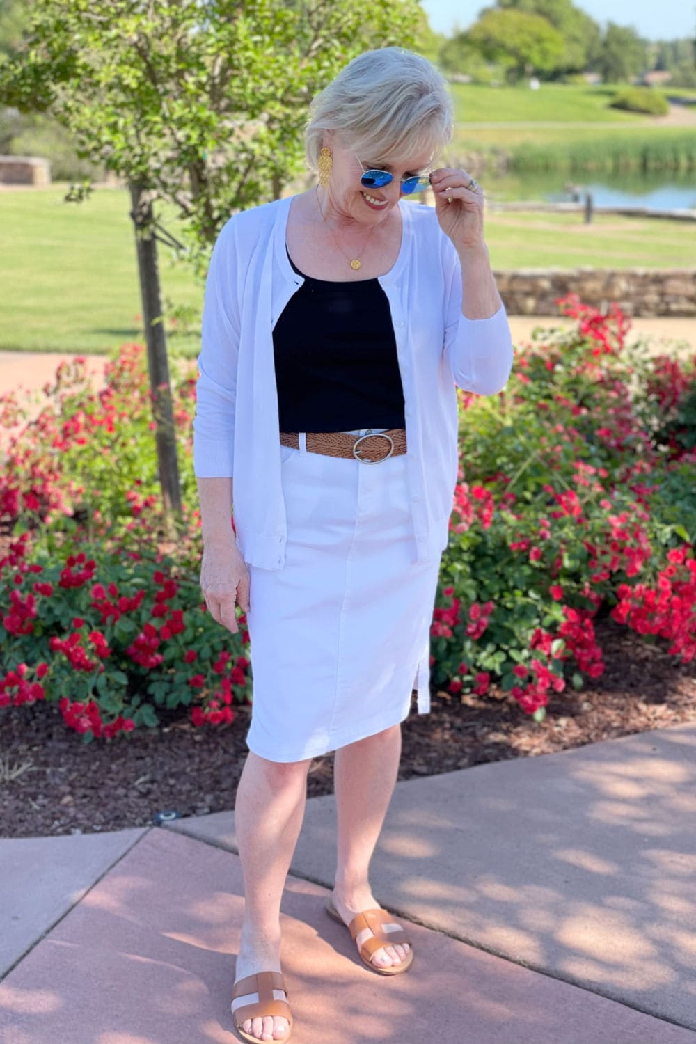 blonde woman on path wearing whote denim skirt, white cardigan and sandals