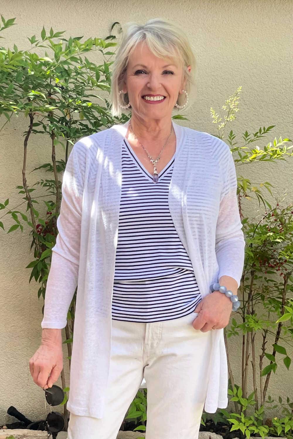 blonde woman wearing striped tee and white line sweater in courtyard garden