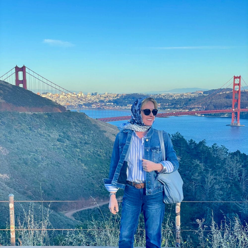 woman standing on bluff above the goldken gate bridge wearign denim jacket and jeans