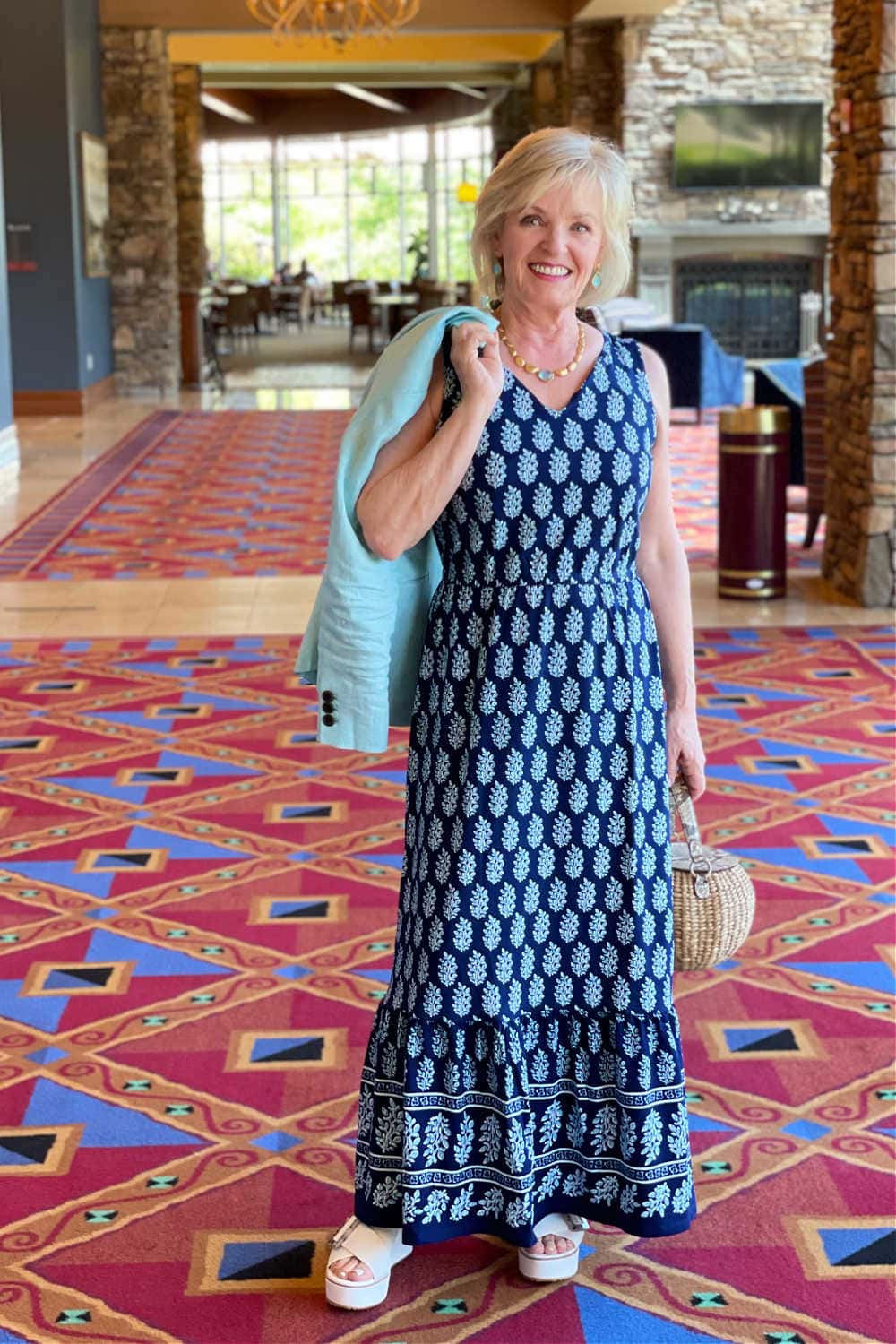 woman stading in hallway wearign paisley dress which a blazer held over her shoulder