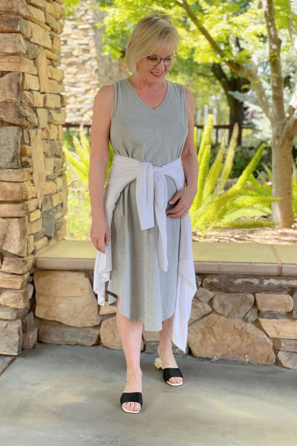 over 50 woman wearing sleevelss dress and white sweater tied at waist