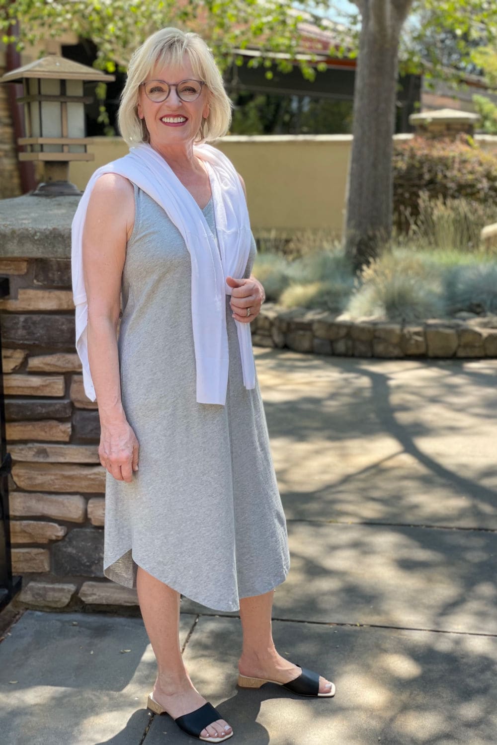 woman wearing gray dress and white sweater with no sleeves