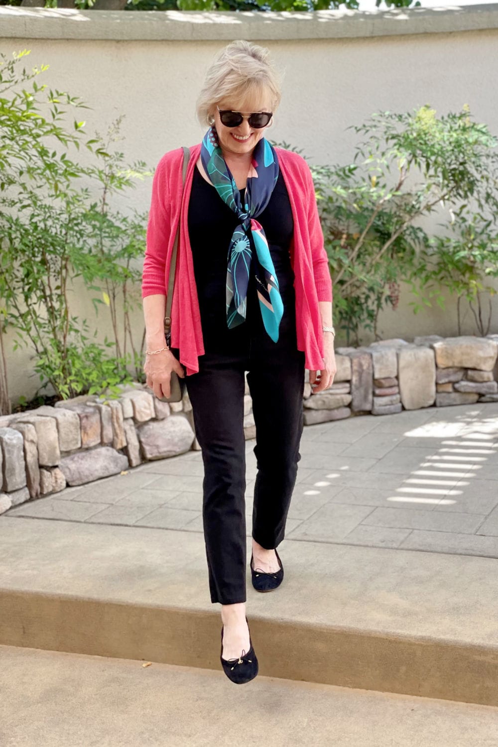 woman stepping down step in pink sweater and black column of color