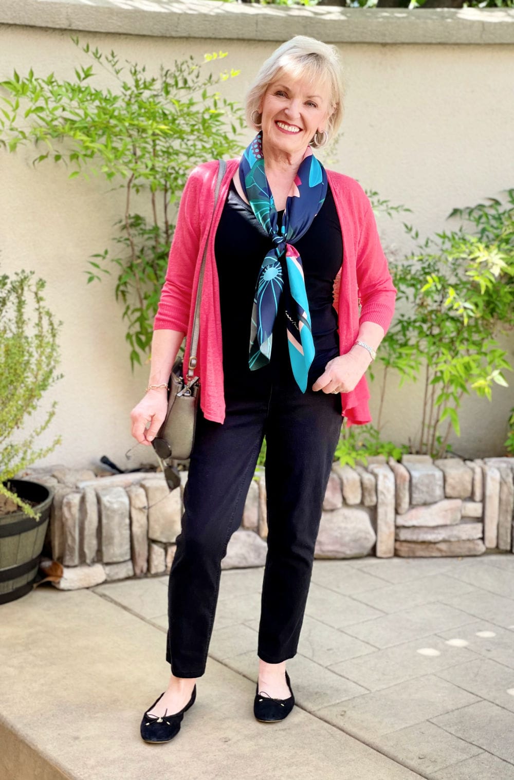 blonde woman wearing black jeans, black top and colorful cardigan