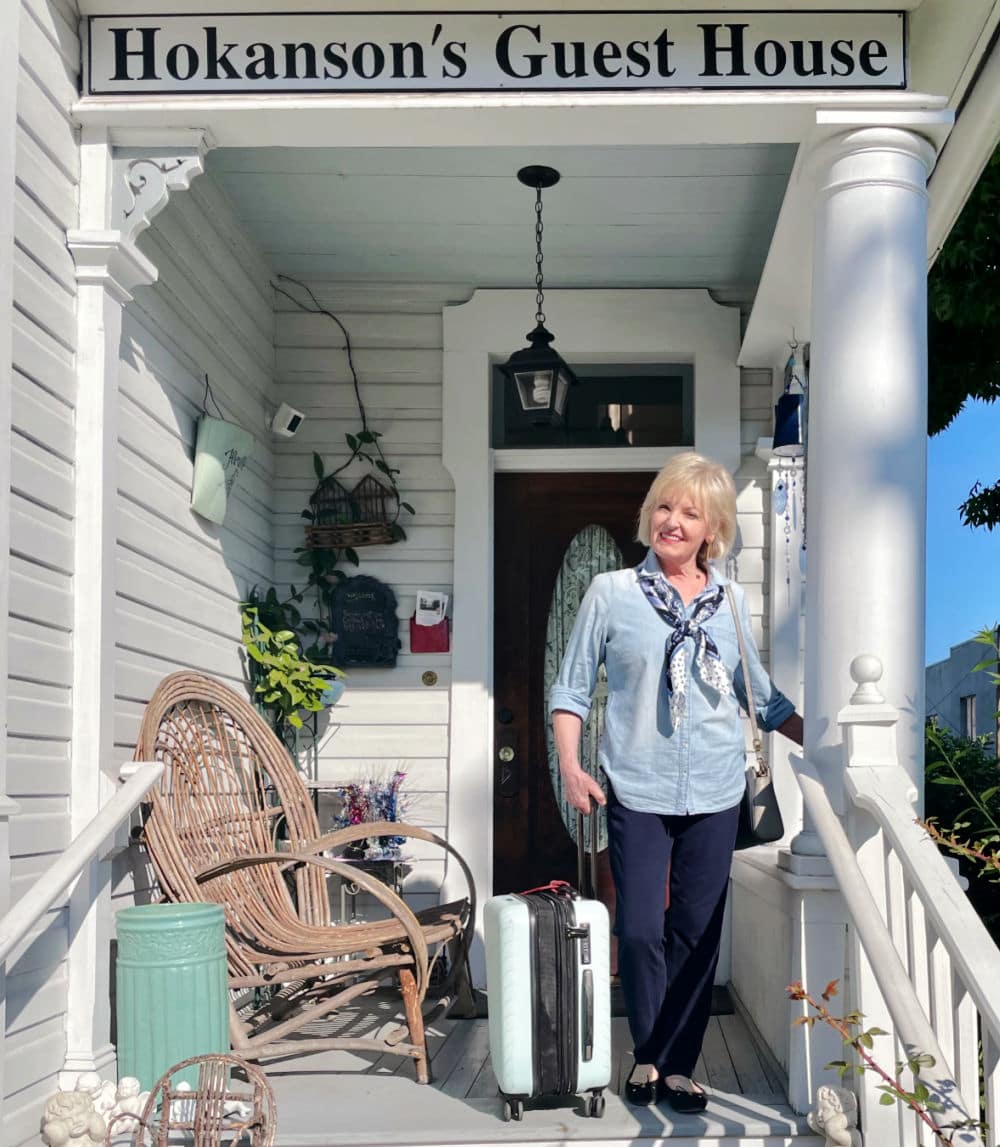 woman on porch of bed and breakfast with luggage