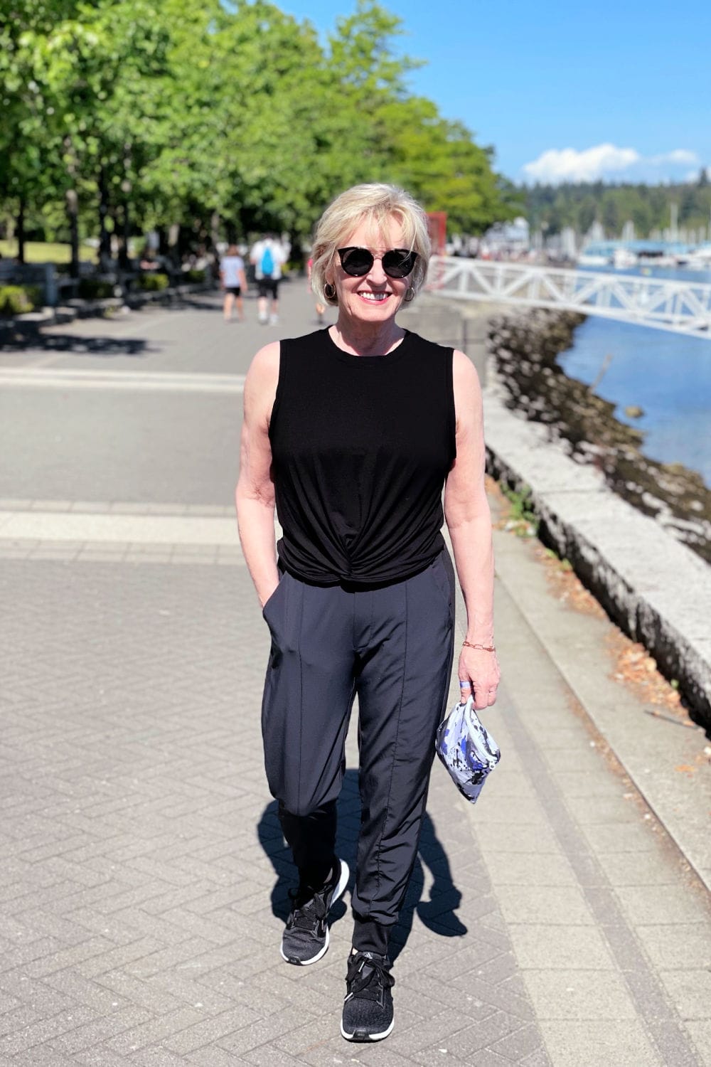 blond woman walking along sea wall with hand on pocket of Zella pants
