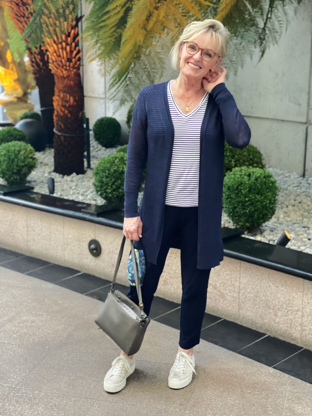 woman wearing navy cardigan and pants with metallic sneakers