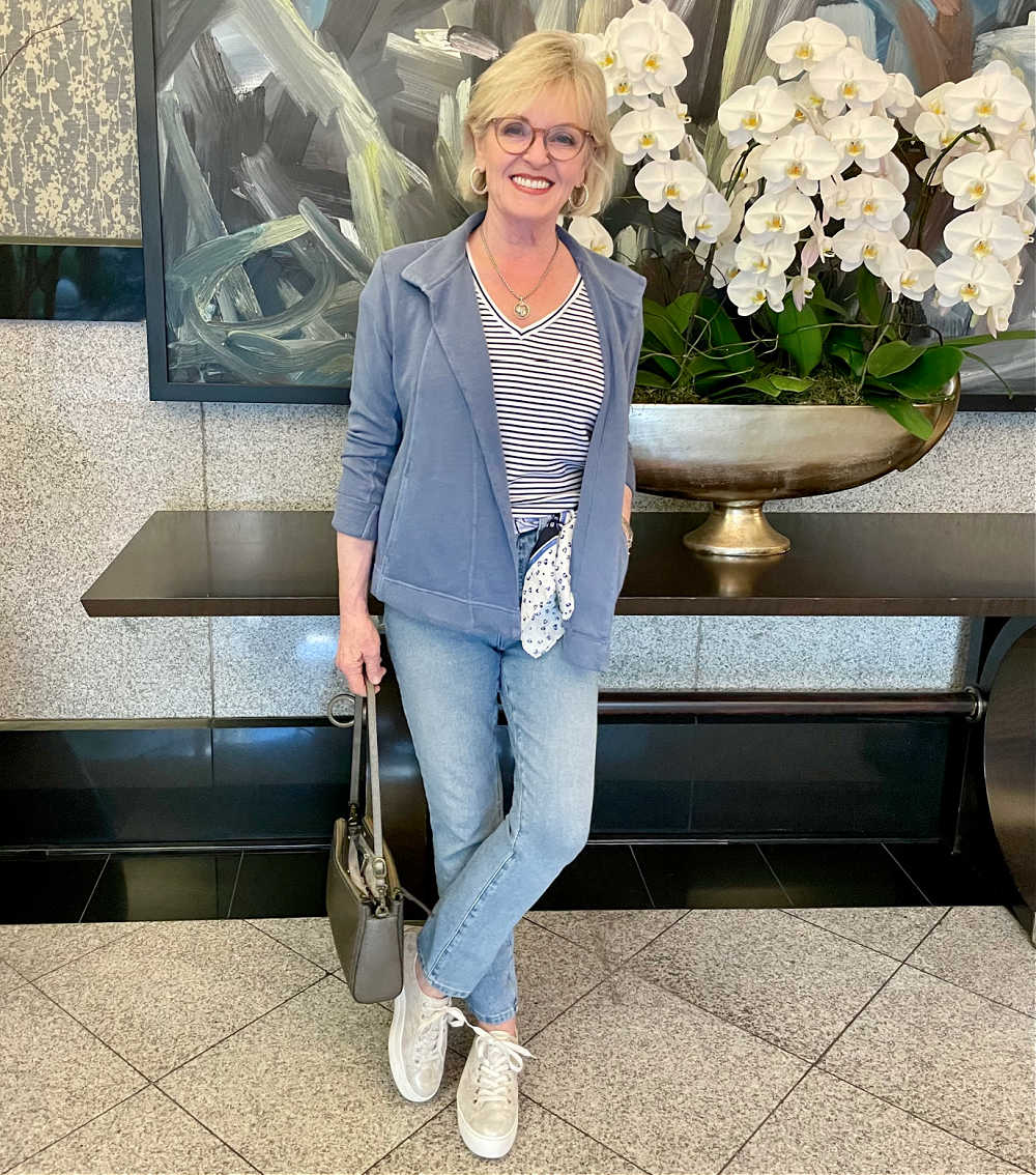 woman leaning against table wearing blue knit jacket, striped tee and madewell jeans