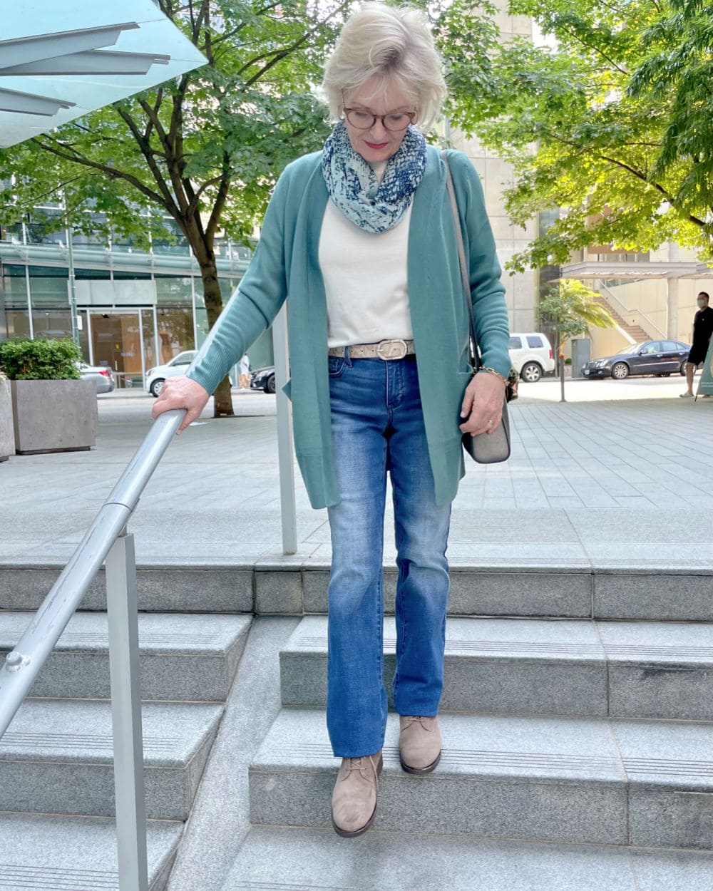 woman walking down stairs wearing teal sweater and nydj jeans from the Nsale