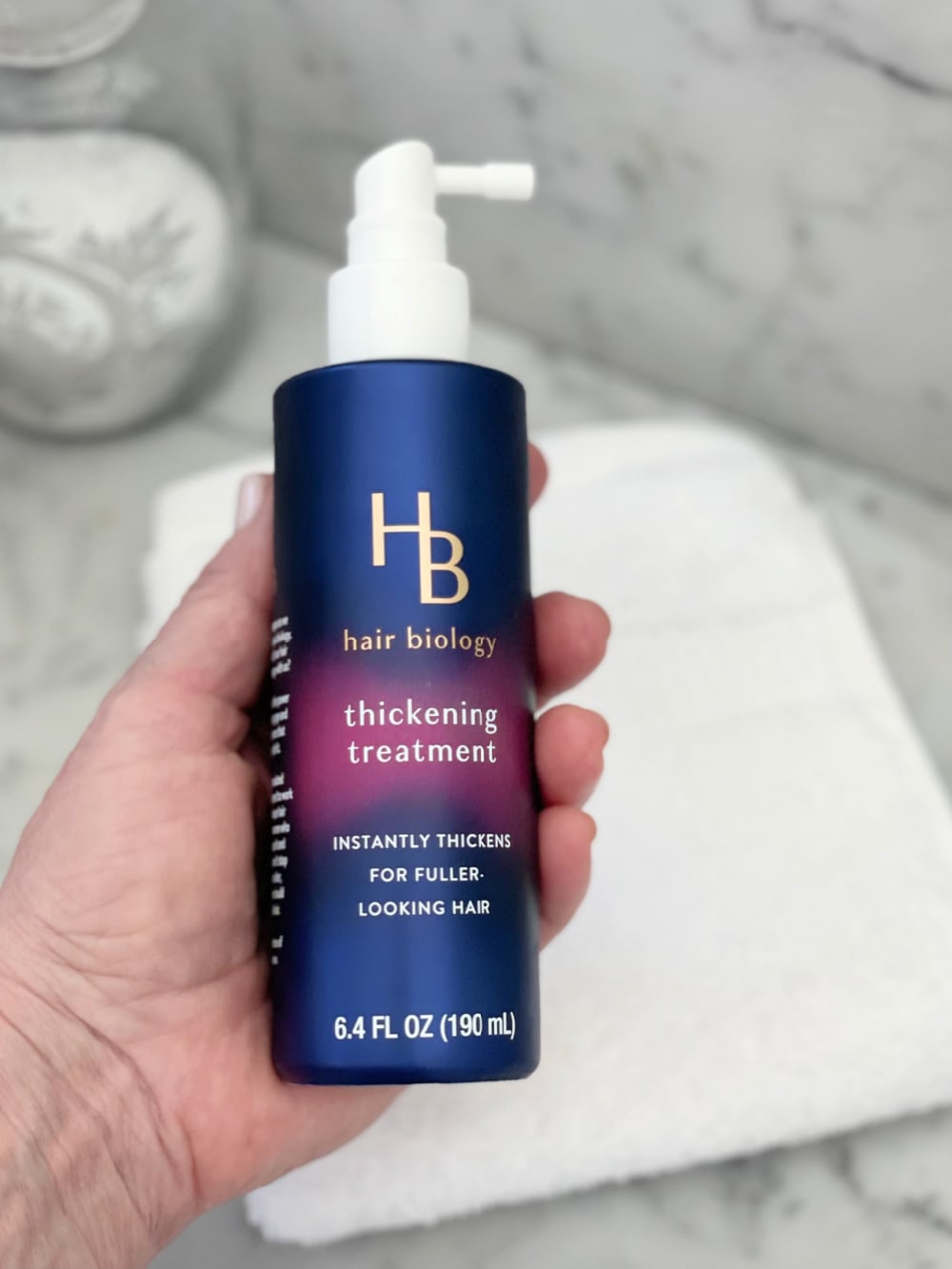 hand holding Hair Biology treatment to make hair look thicker