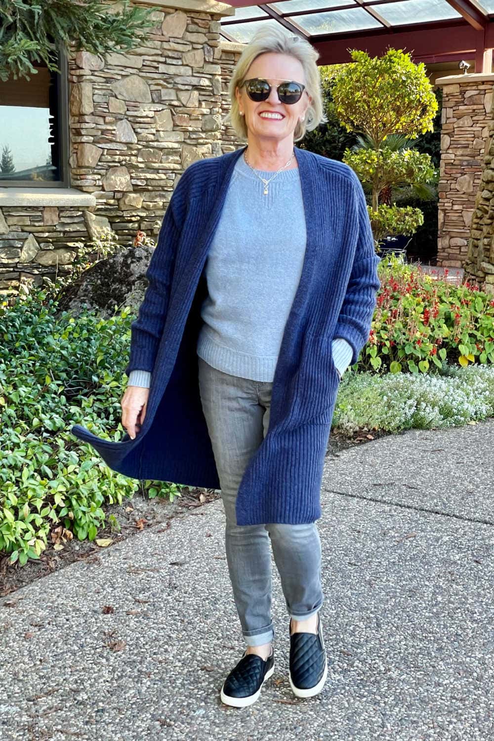 woman walking wearing target long blue sweater grey jeans and black sneakers