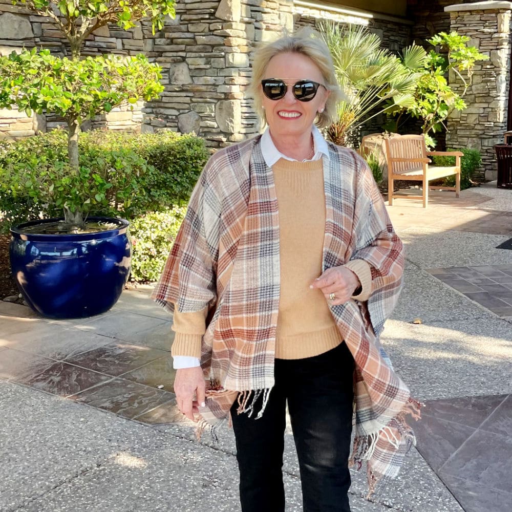 woman walking in plaid ruana and beige sweater