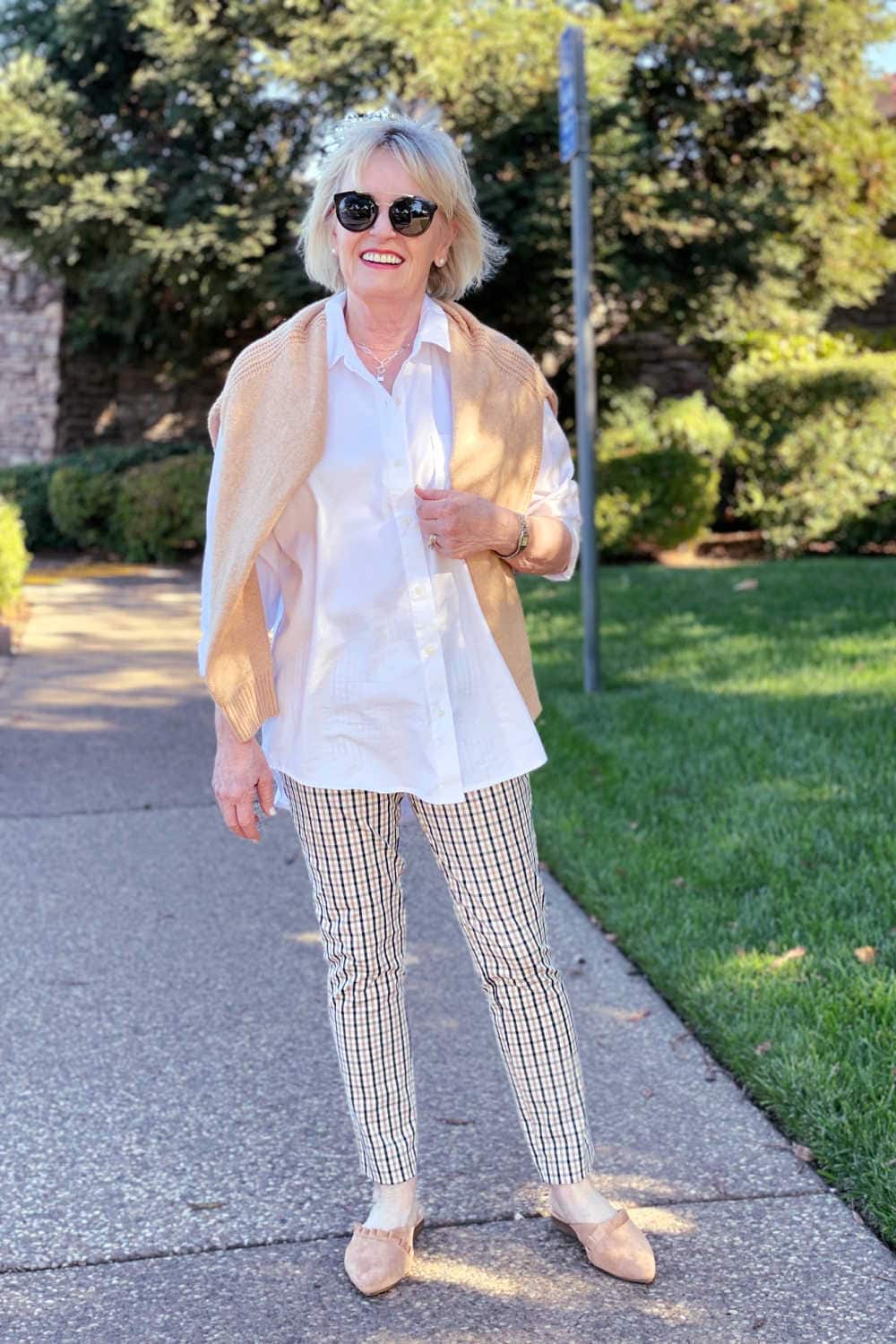 woman wearing white tunic shirt, plaid pants and camel colored slides