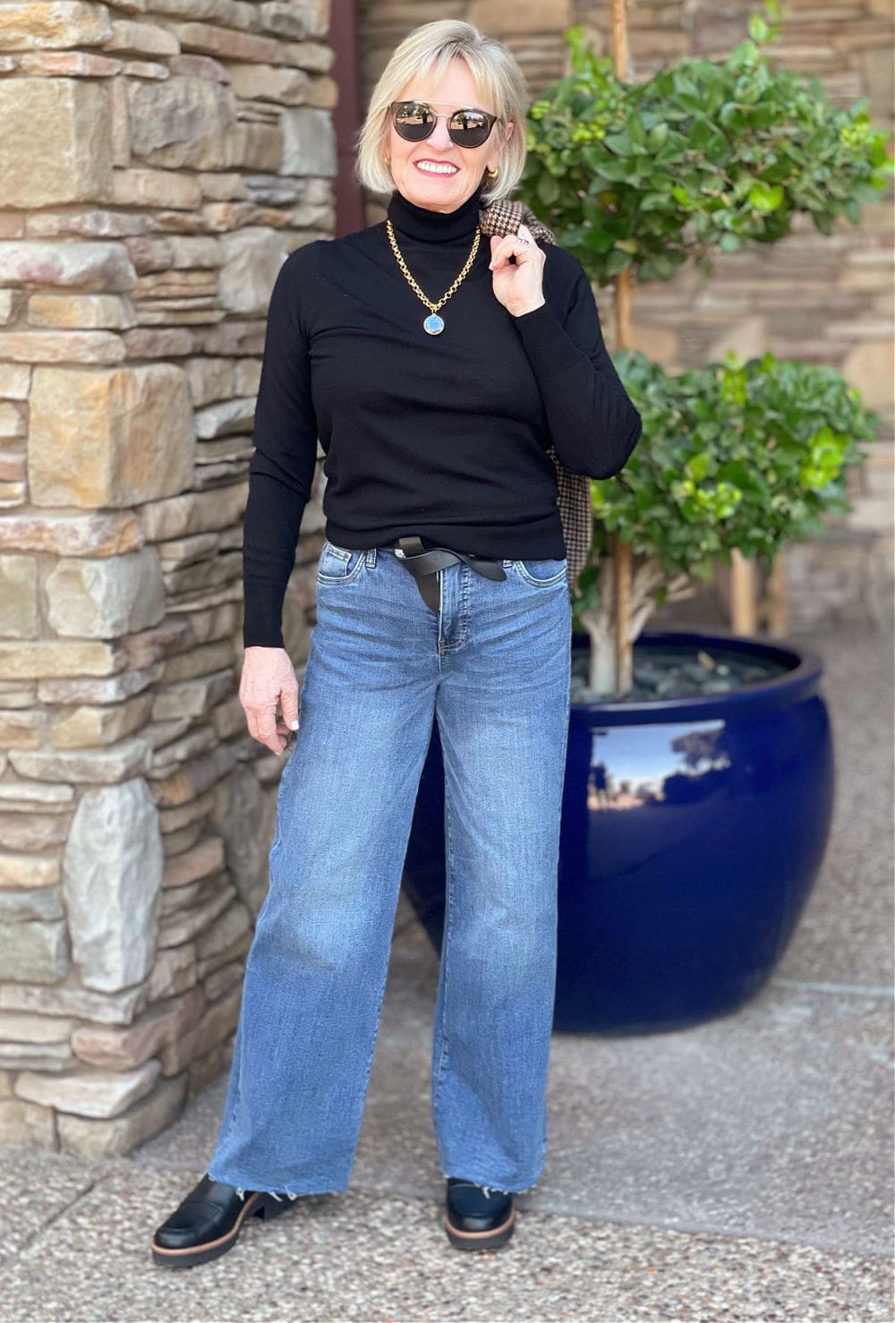 over 50 fashion blogger wearing black turtleneck and wide leg jeans