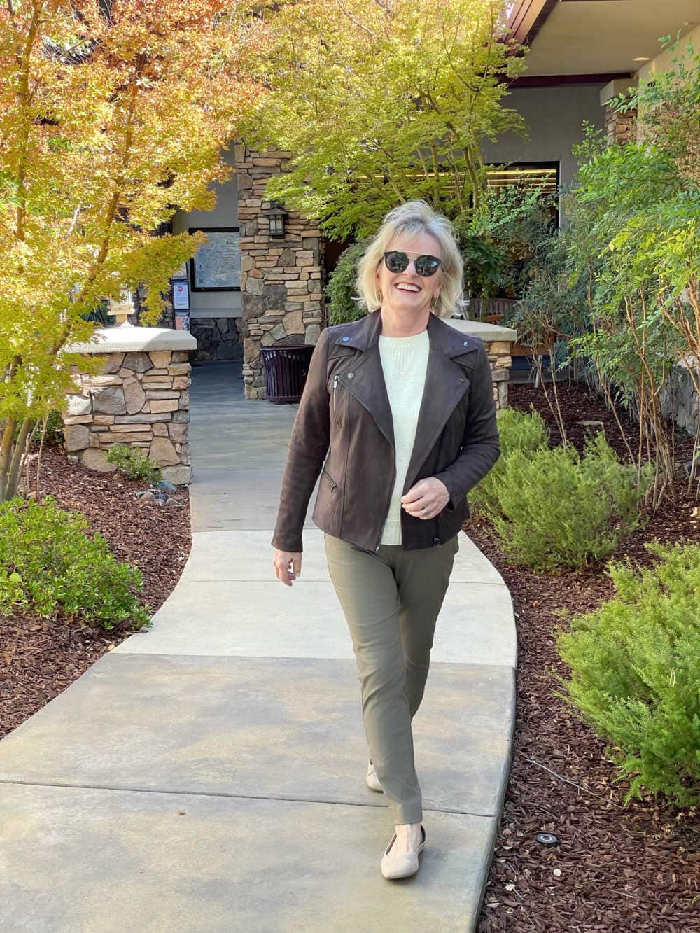 blonde woman walking wearing brown faux suede moto jacket outfit