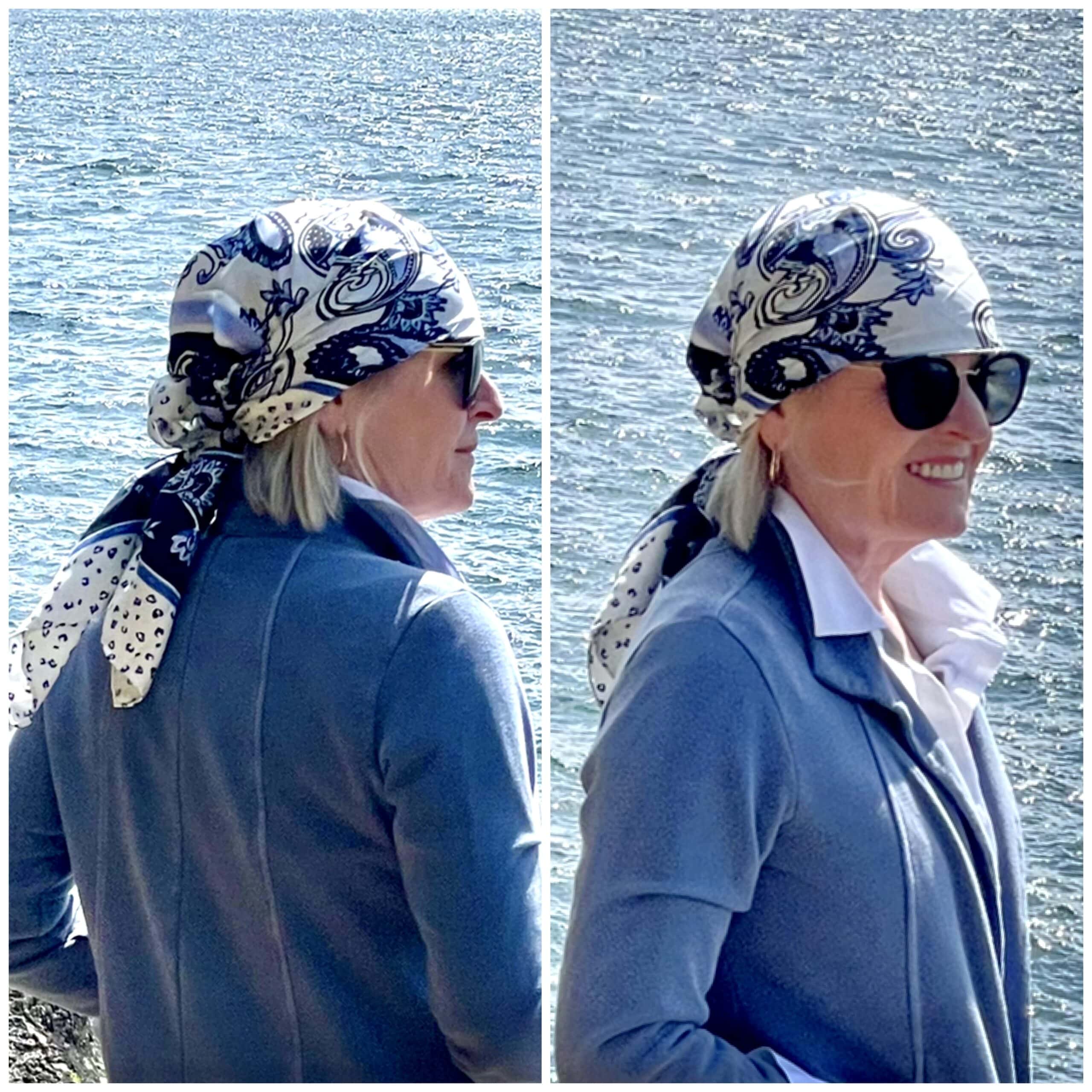 over 50 woman showing front and back of blue and white head scarf wrap while standing on the coastline