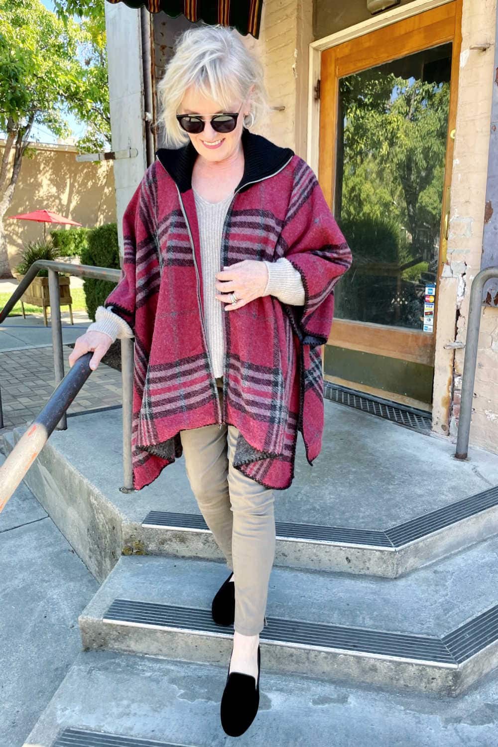 woman going down stairs wearing redelvet birdies plaid pncho and black v