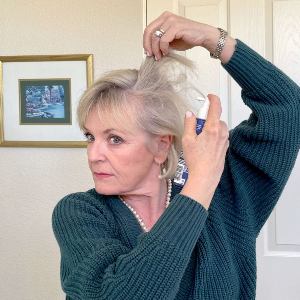woman applying hair biology thickening spray at roots of her hair