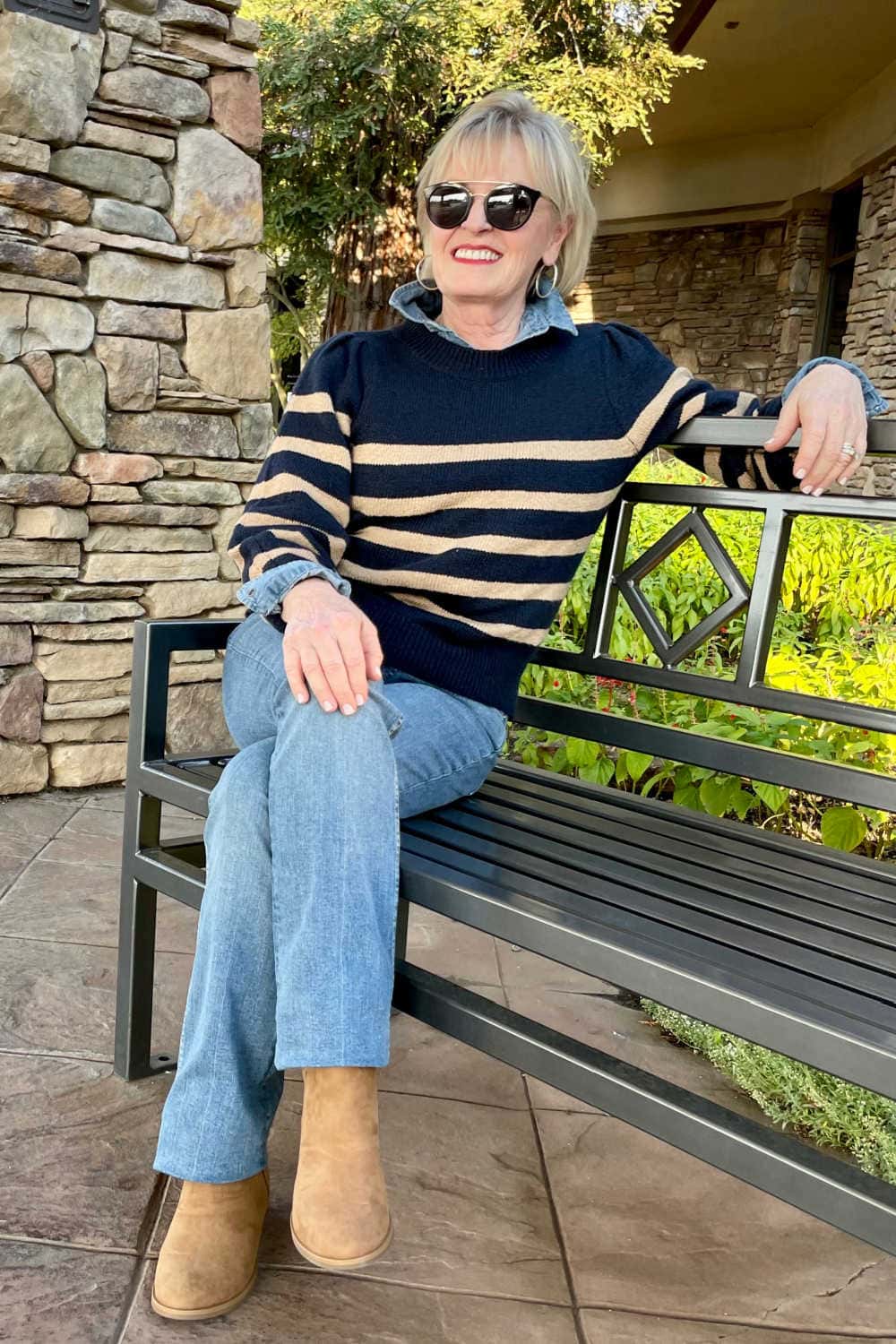 ench wearing camel suede booties, bootcut jeans and navy stripe pullover woman sitting on b