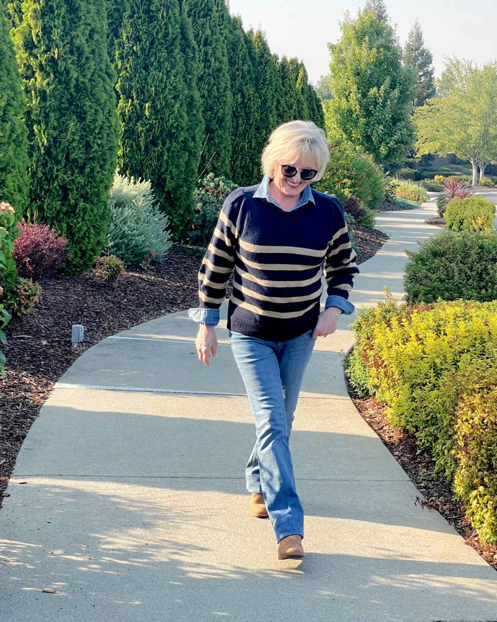 woman walking wearing striped free assembly sweater denim shirt and jeans