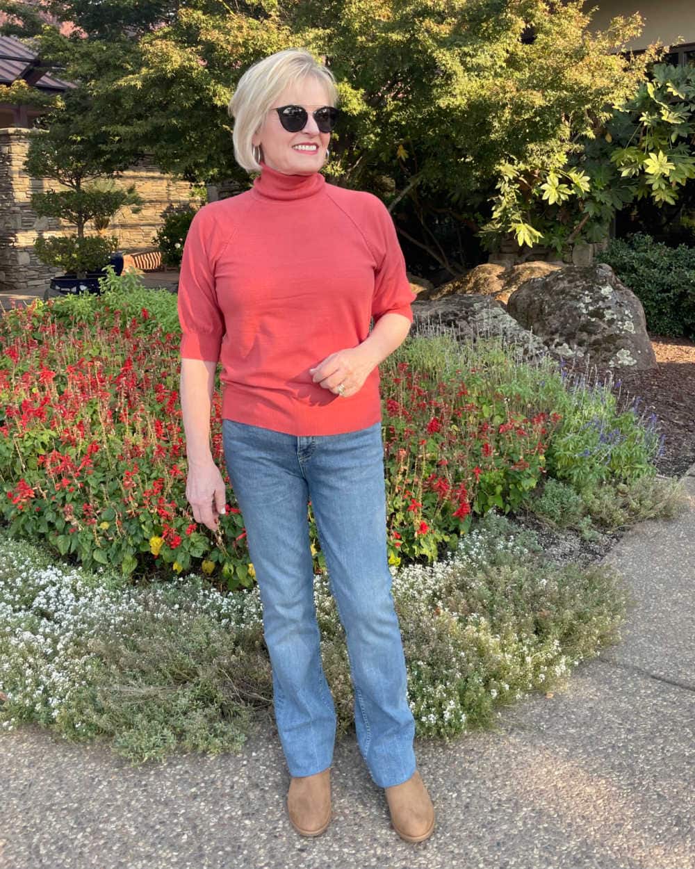 blond woman wearing coral sweater and blue jeans
