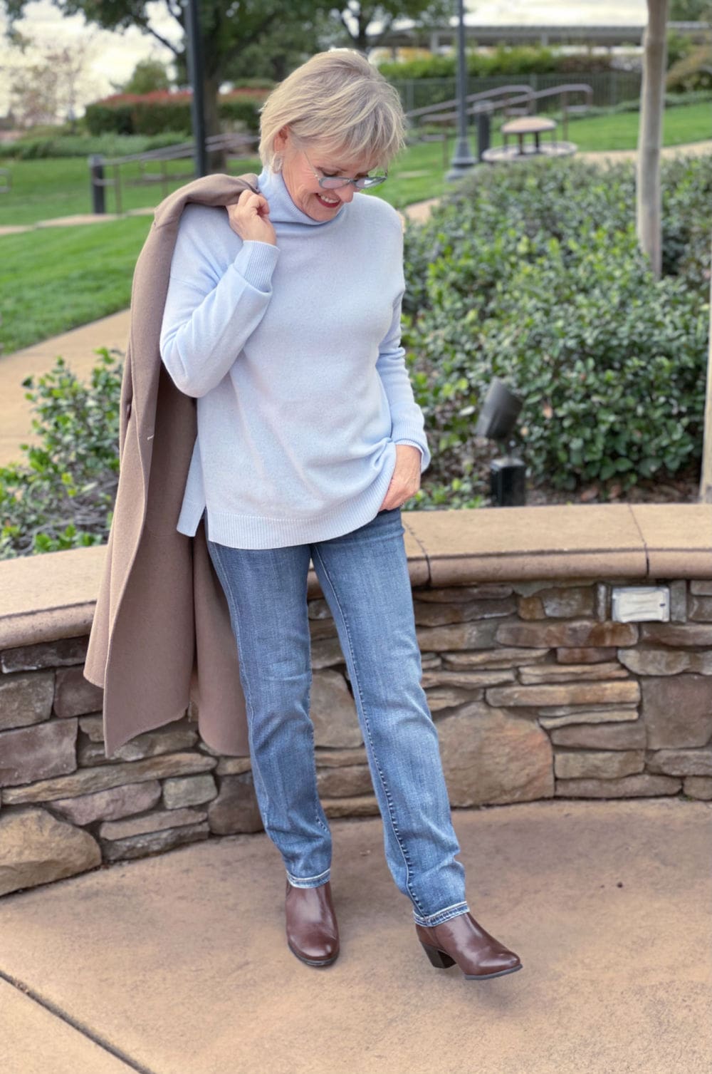WOMAN HOLDING UNLINED COAT OVER HER SHOULDER