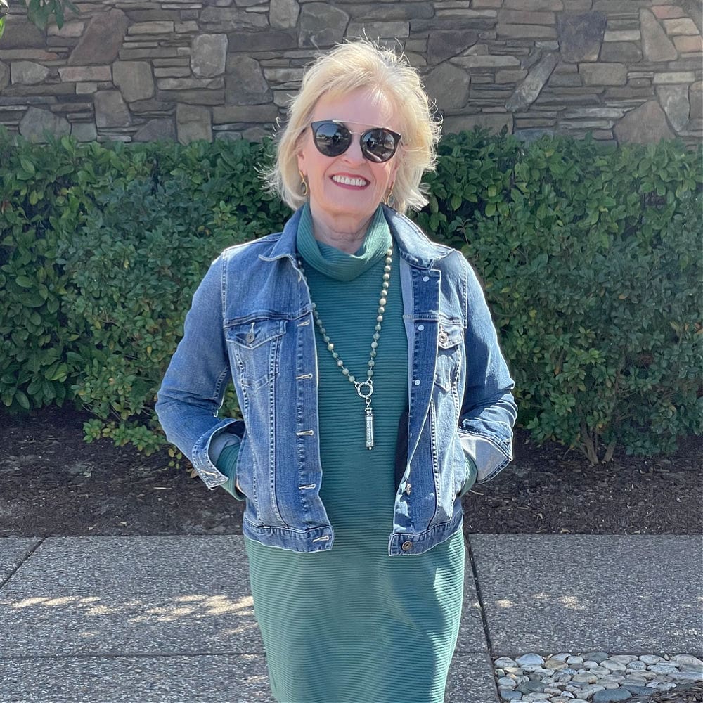 woman wearing denim jacket and teal dress with sunglasses