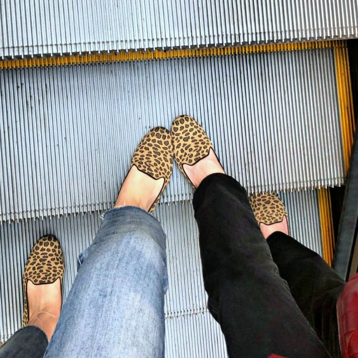 two pair of rothy's aniumal print loafers on escalator