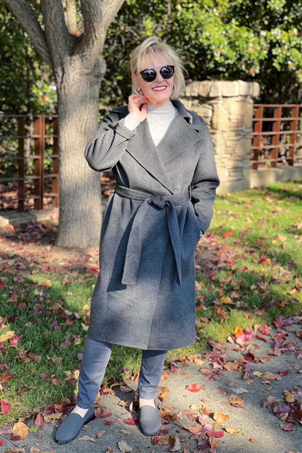 blonde woman wearing column of gray coat and jeans with low contrast