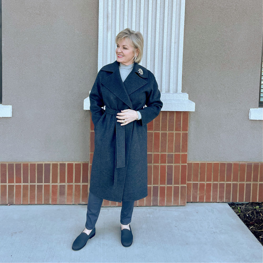 blonde woman standing against brick wall