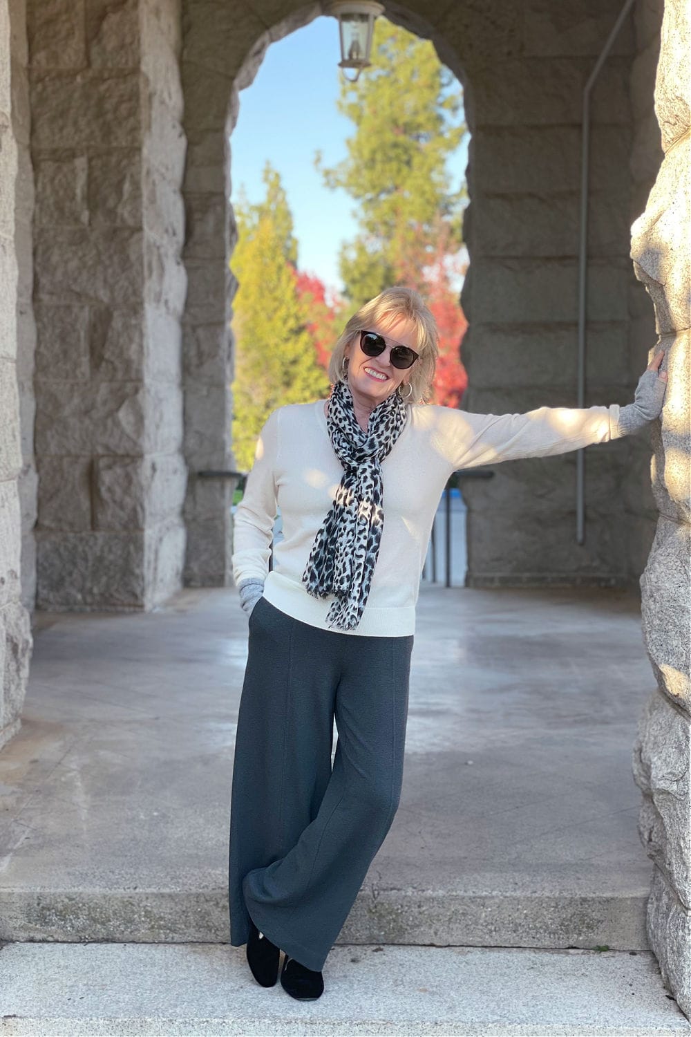 woman leaning on wal wearing gray and cream casual outfit and leopard scarf