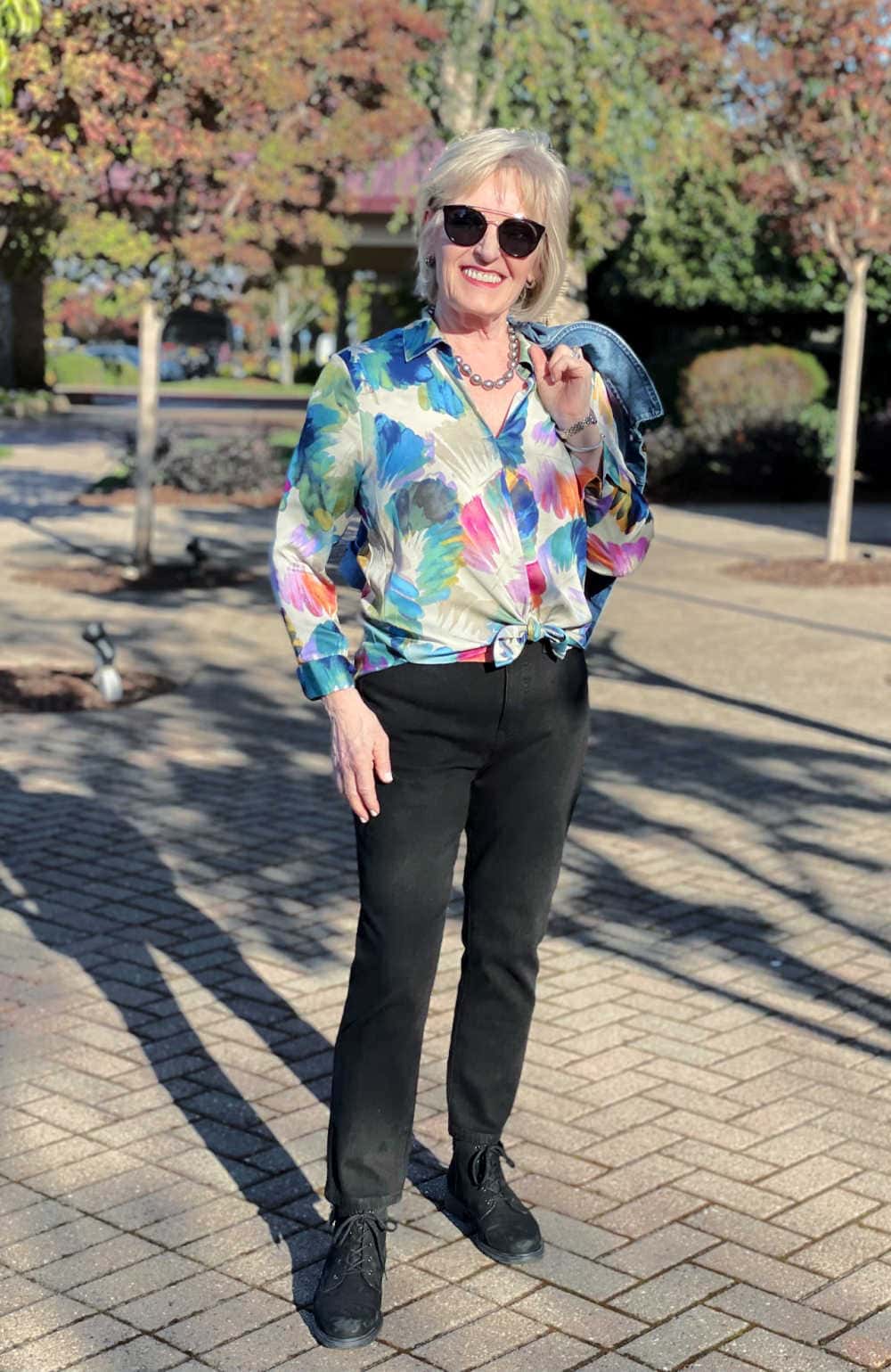 woman wearing floral blouse outfit with black jeans and booties