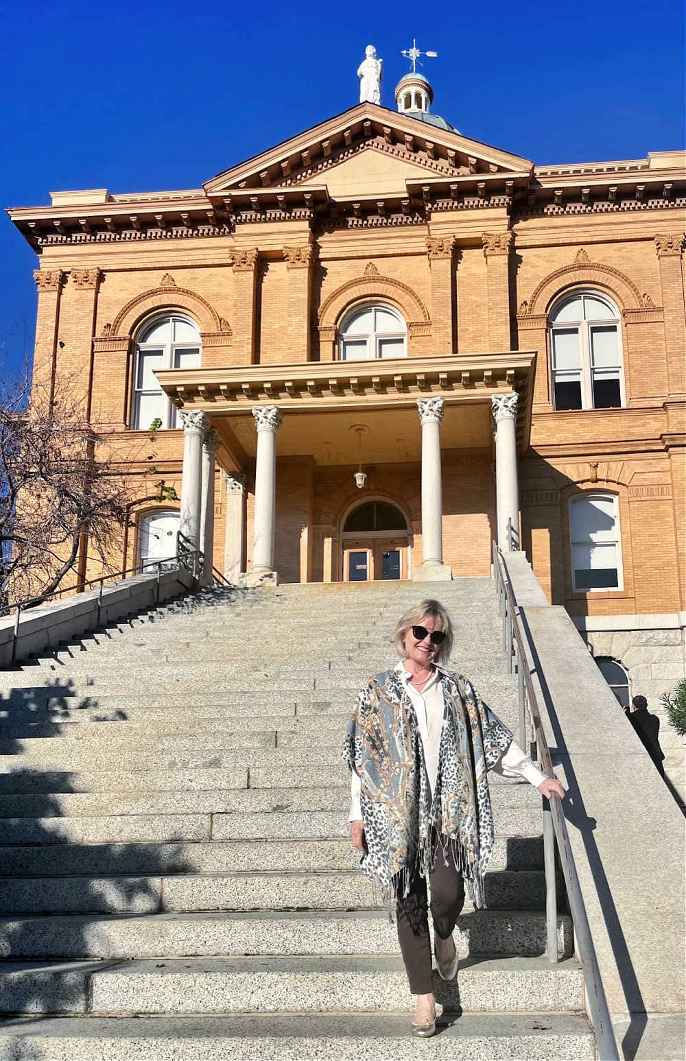 woman standing on stairs of captial bulding weariong soft muted outfit