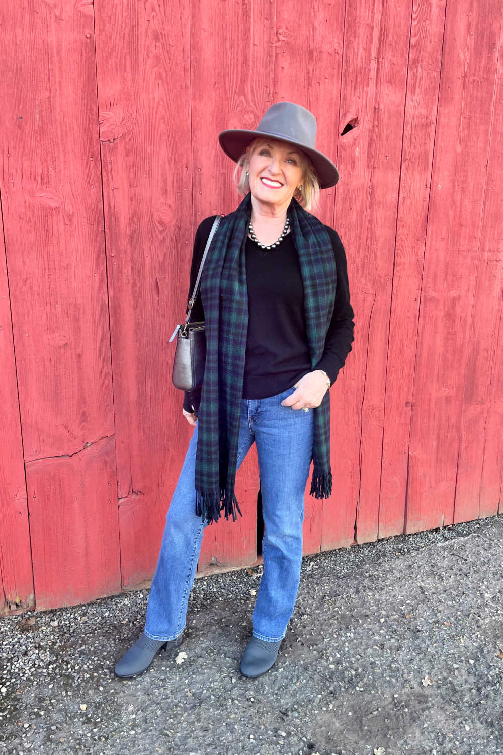 woman in front of red wall wearing jeans and gray fedora visiting murphy's ca