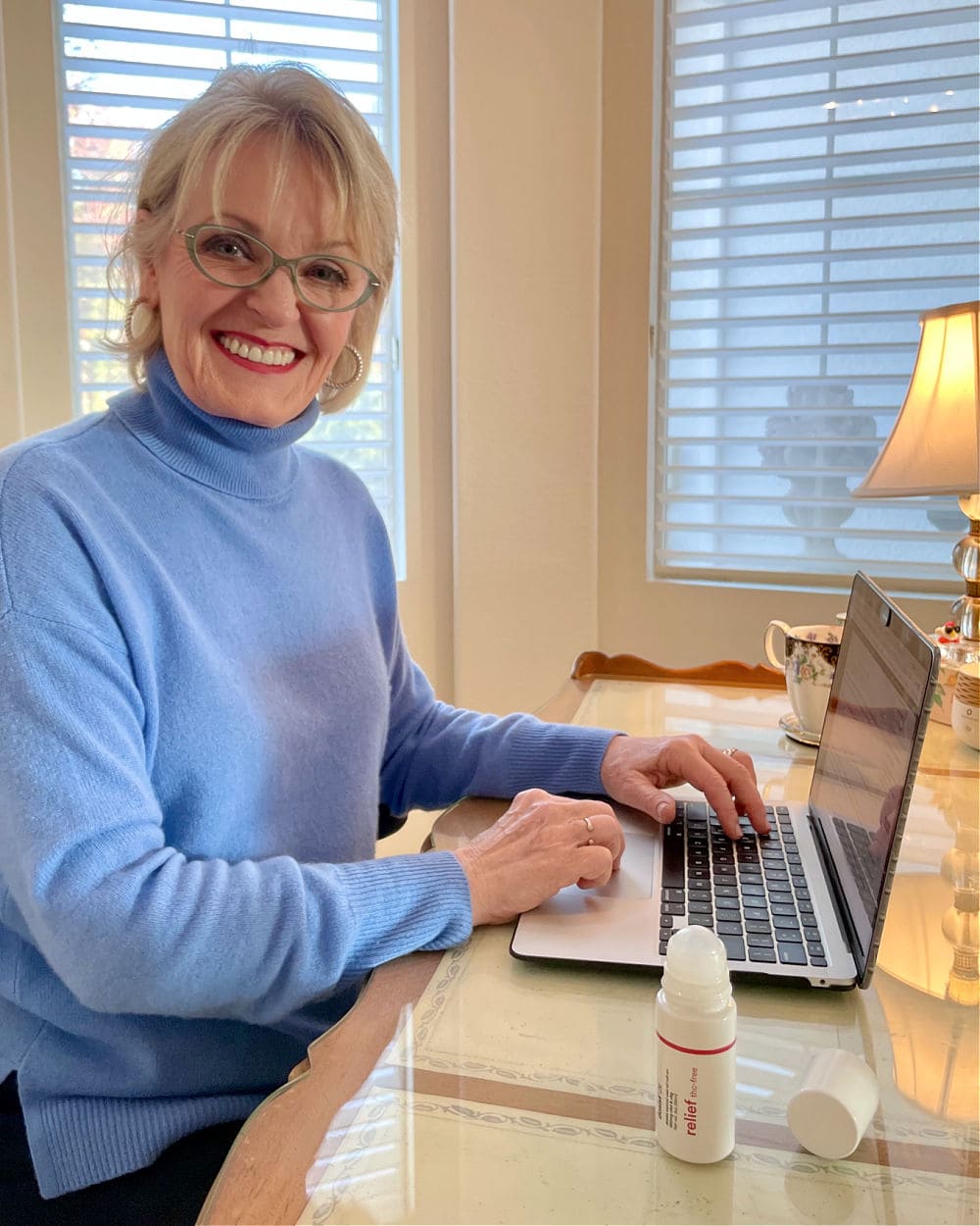 woman sitting at laptop after applying dosist health relief roll-on
