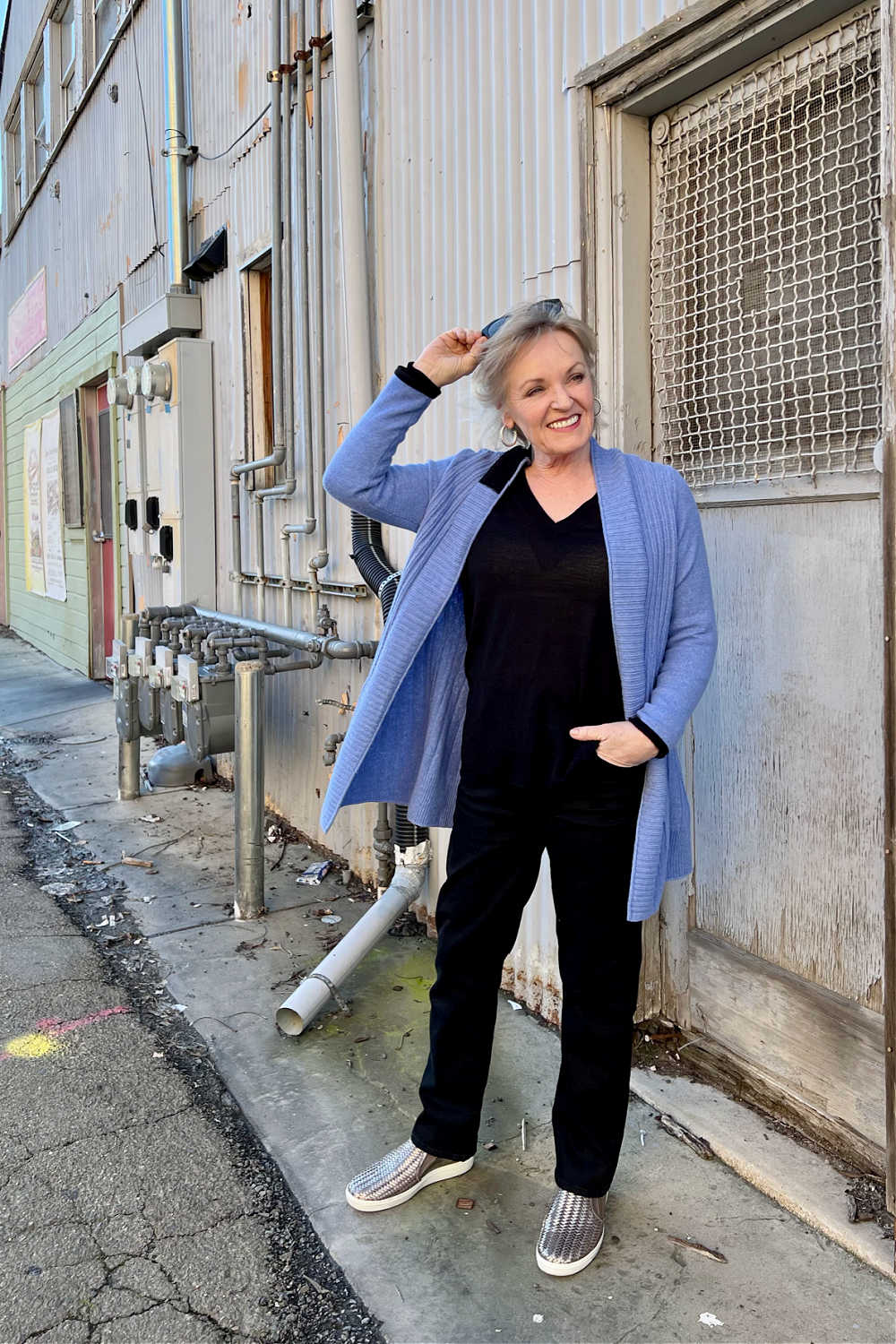 woman leanign on wall in blue cardigan