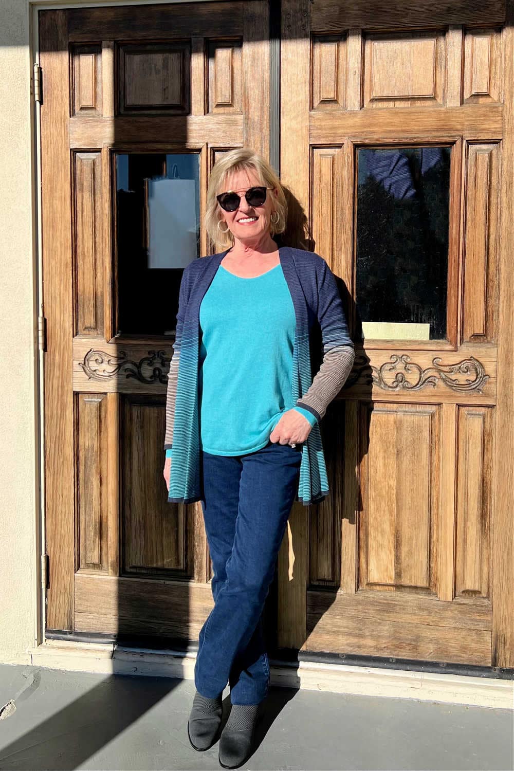 woman leaning against door in turquoise sweater